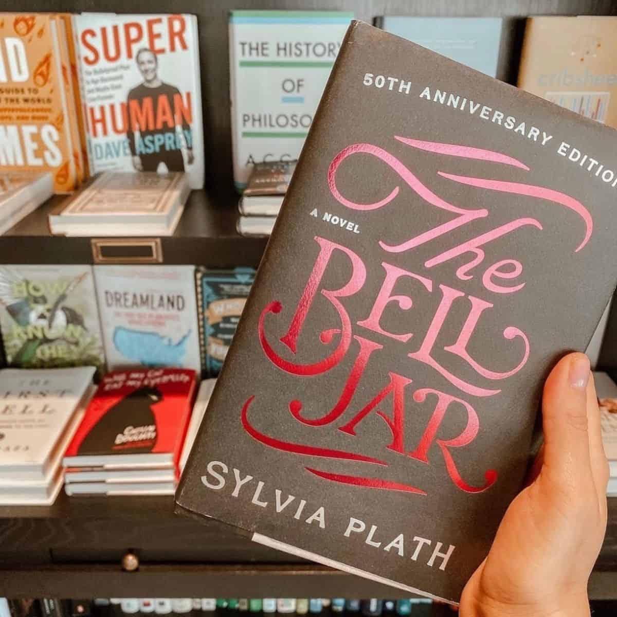 the bell jar by sylvia plath in front of a bookshelf.