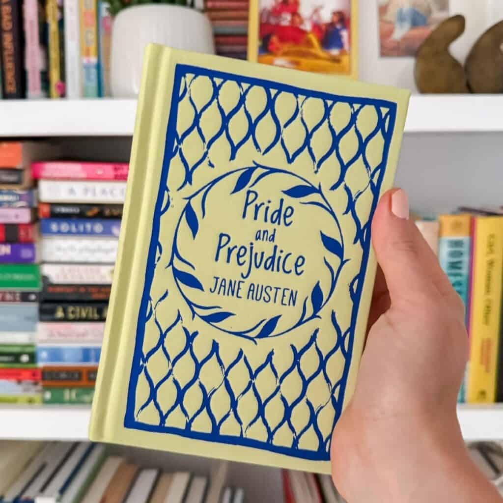 pride and prejudice by jane austen in front of a bookshelf.
