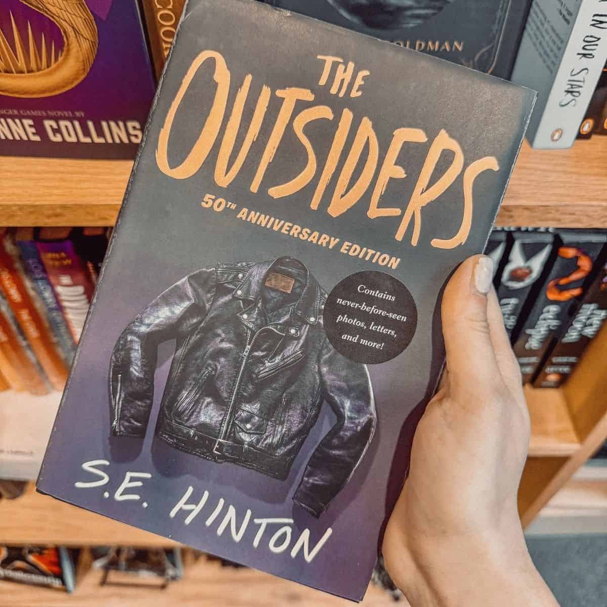 the outsiders by s.e. hinton in front of a bookshelf.